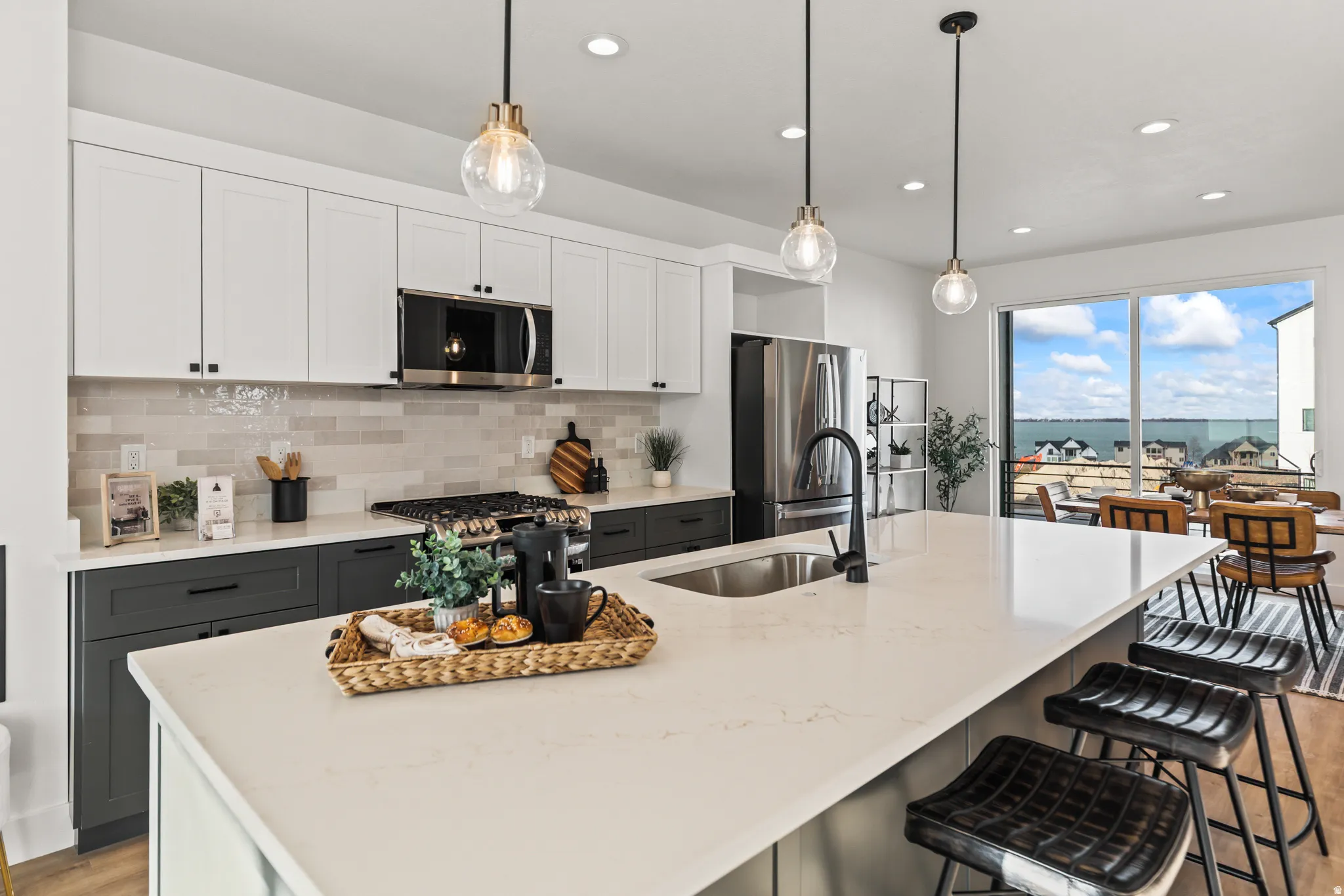 Spacious kitchen featuring an expansive island, stainless steel appliances, a tile backsplash, and two-tone cabinetry with modern hardware