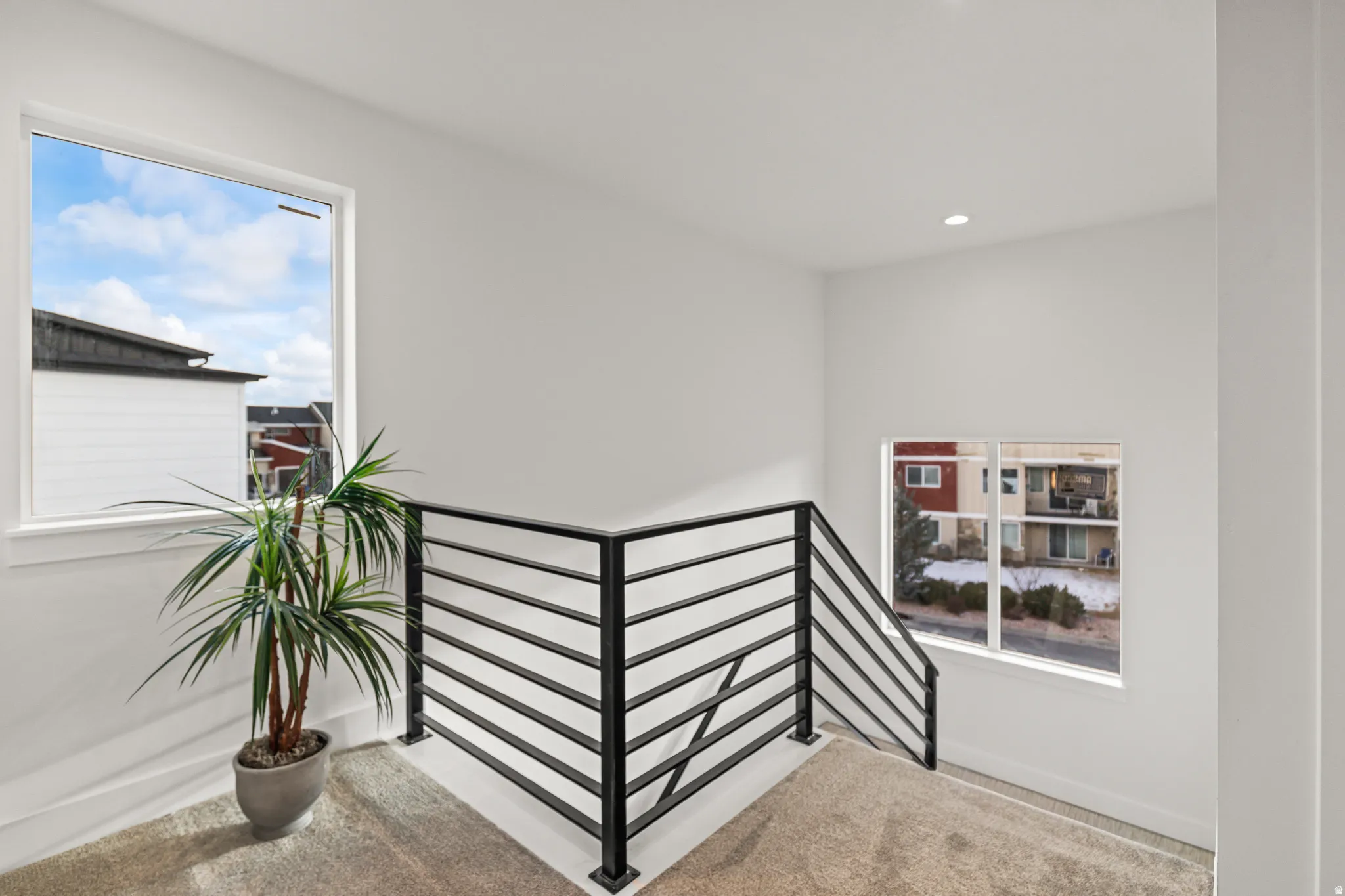 White walls, recessed lighting, and a horizontal bar railing