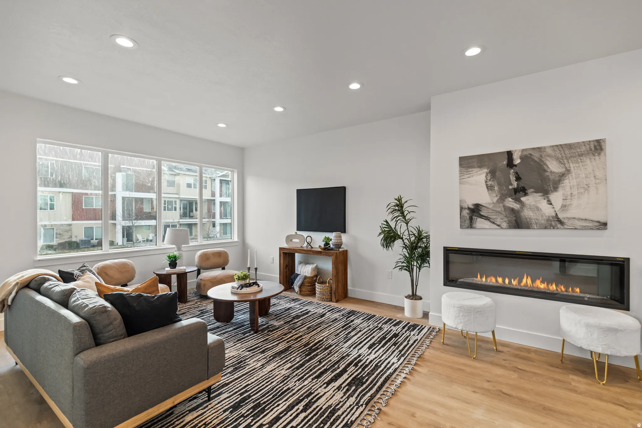 Living area featuring a linear gas fireplace, recessed lighting, and large windows with white trim