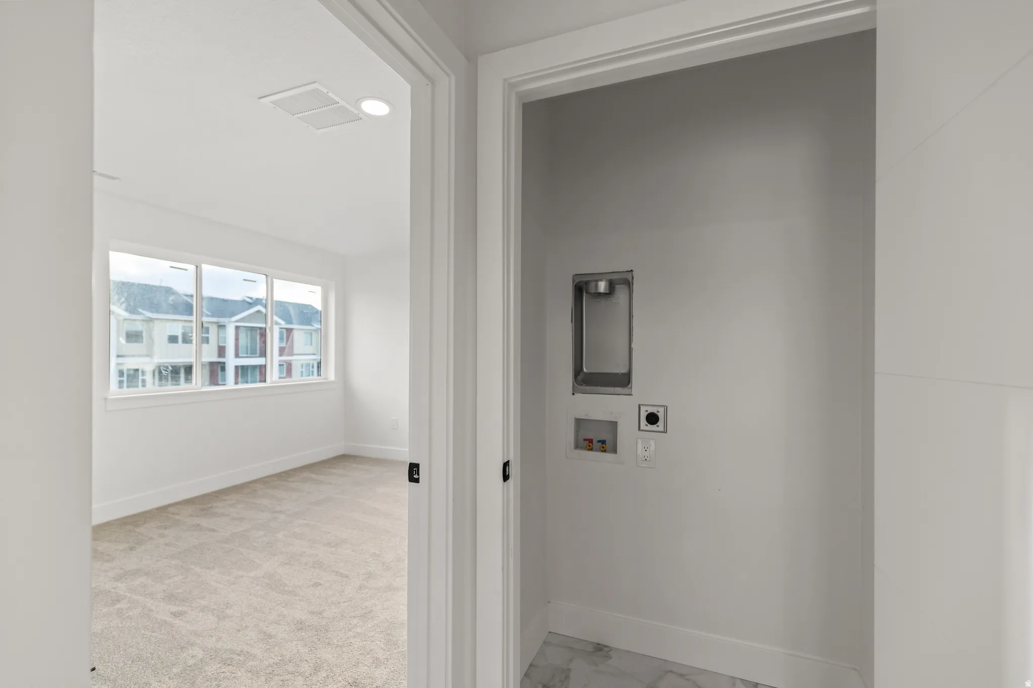 Carpeted room with a three-panel window, white walls, and a ceiling light fixture