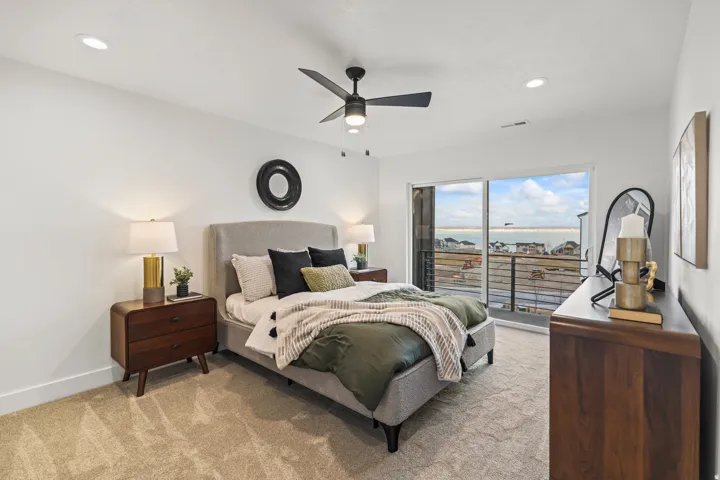 Sliding glass door, private balcony with metal railing, recessed lighting, ceiling fan, and light-colored carpet