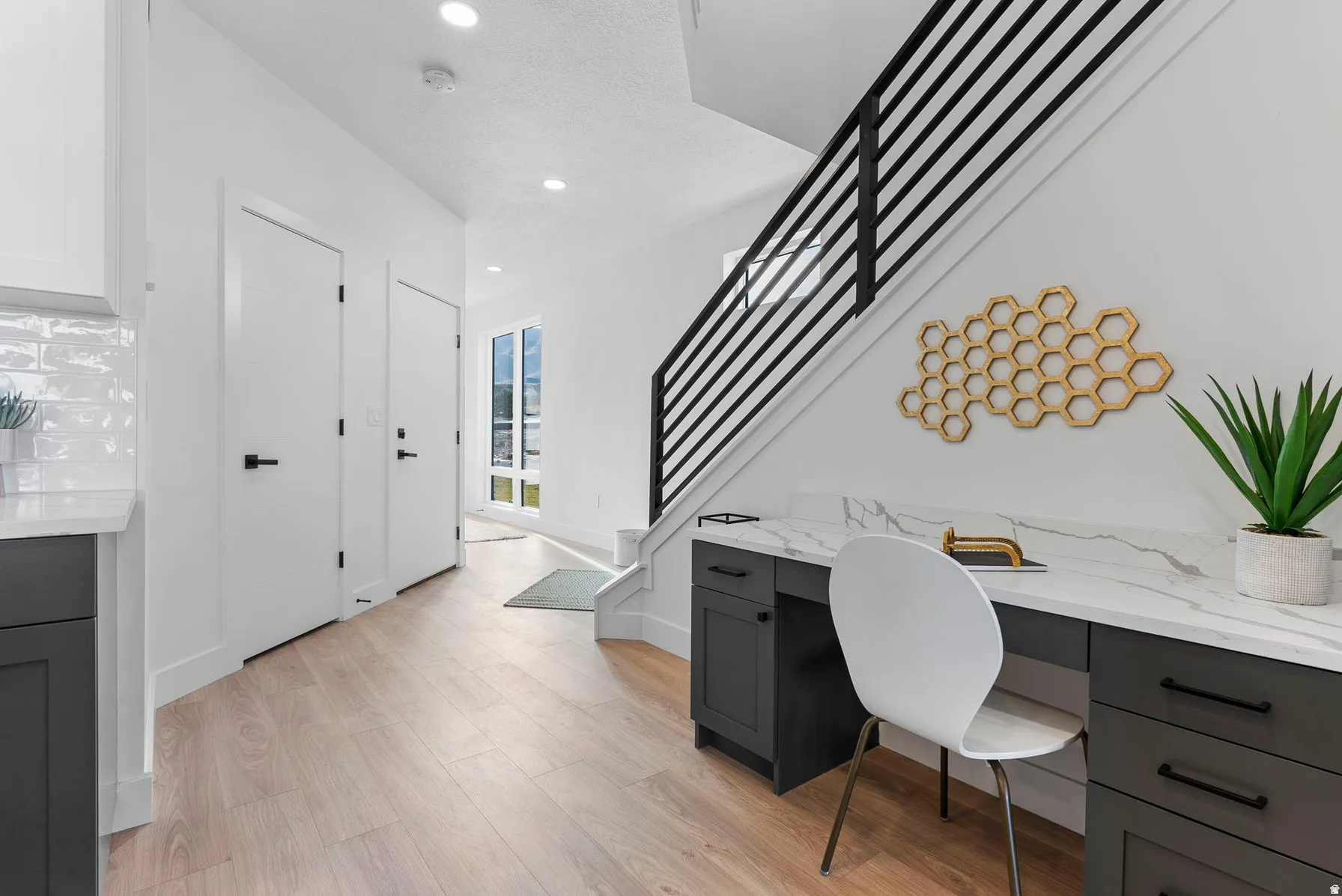 Integrated desk with a stone-finish countertop, dark cabinetry, and wood-finish flooring