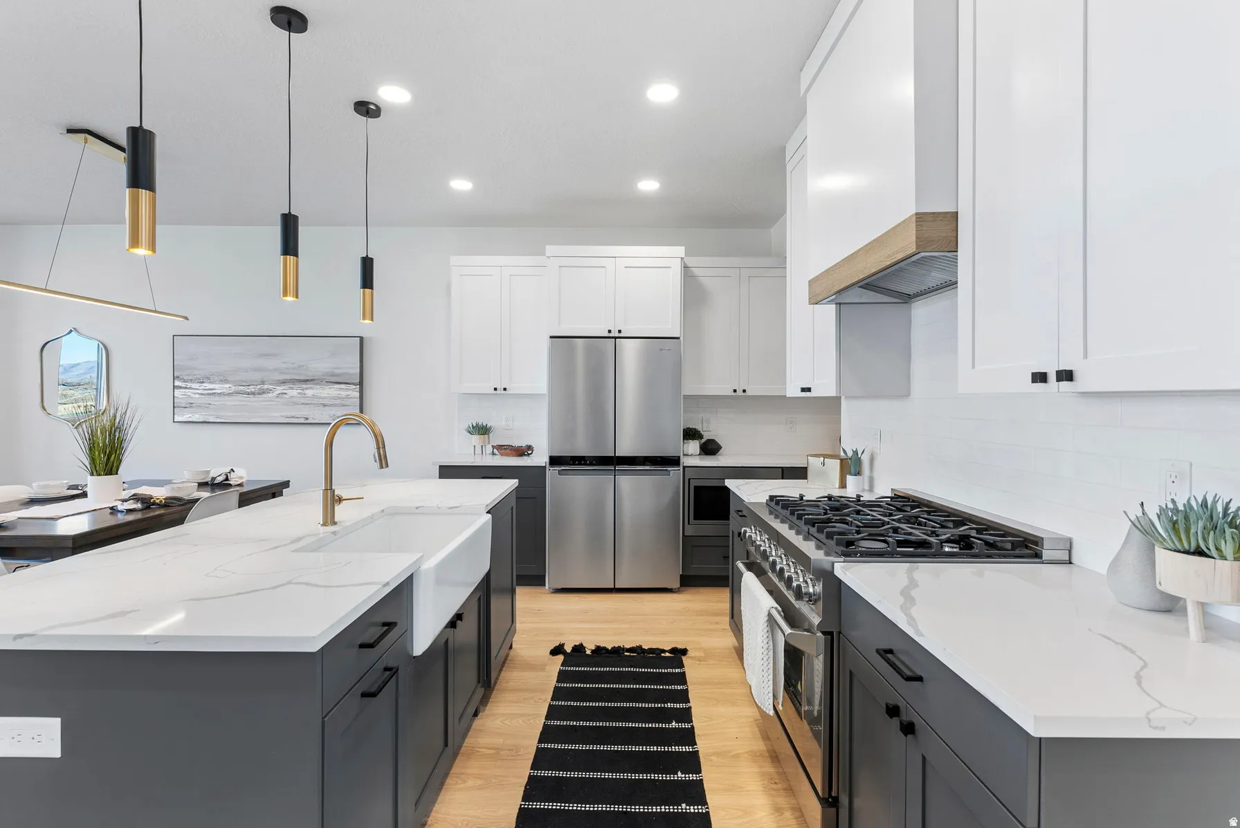 Gourmet kitchen featuring a large island, white apron-front sink, stainless steel appliances, and wood-finish flooring