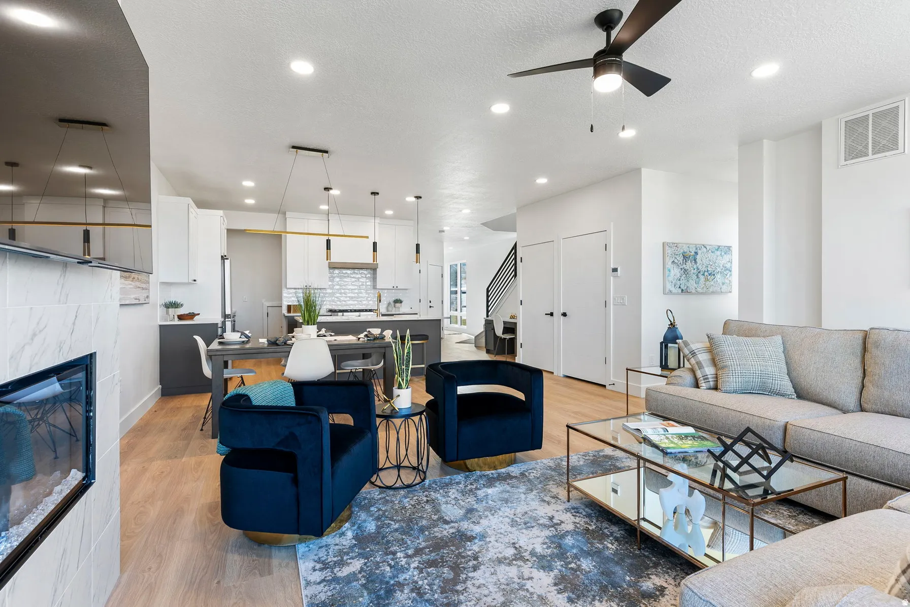 Open concept living area with wood-finish flooring, a built-in fireplace featuring tile surround, and a ceiling fan