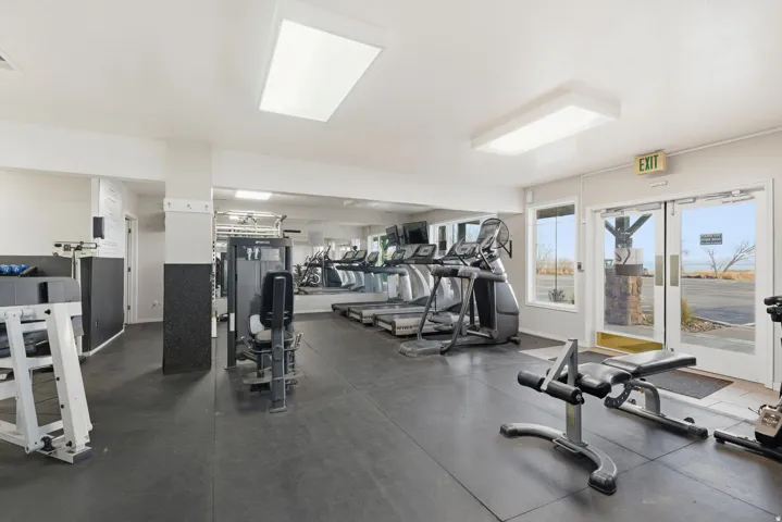 Dedicated fitness space featuring rubber flooring, large mirrors, and multiple windows