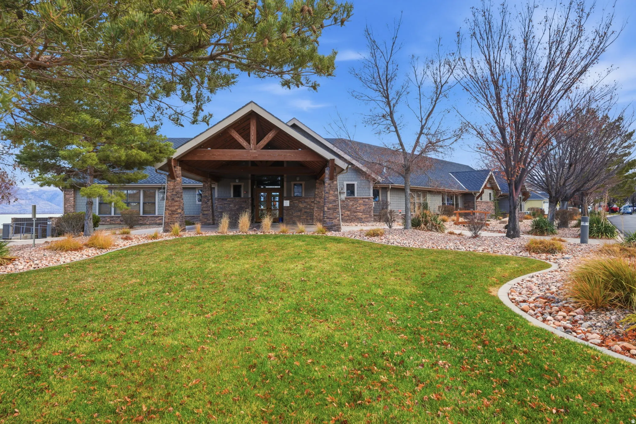Stone and siding exterior with a covered entry, gabled roofline, and landscaped grounds