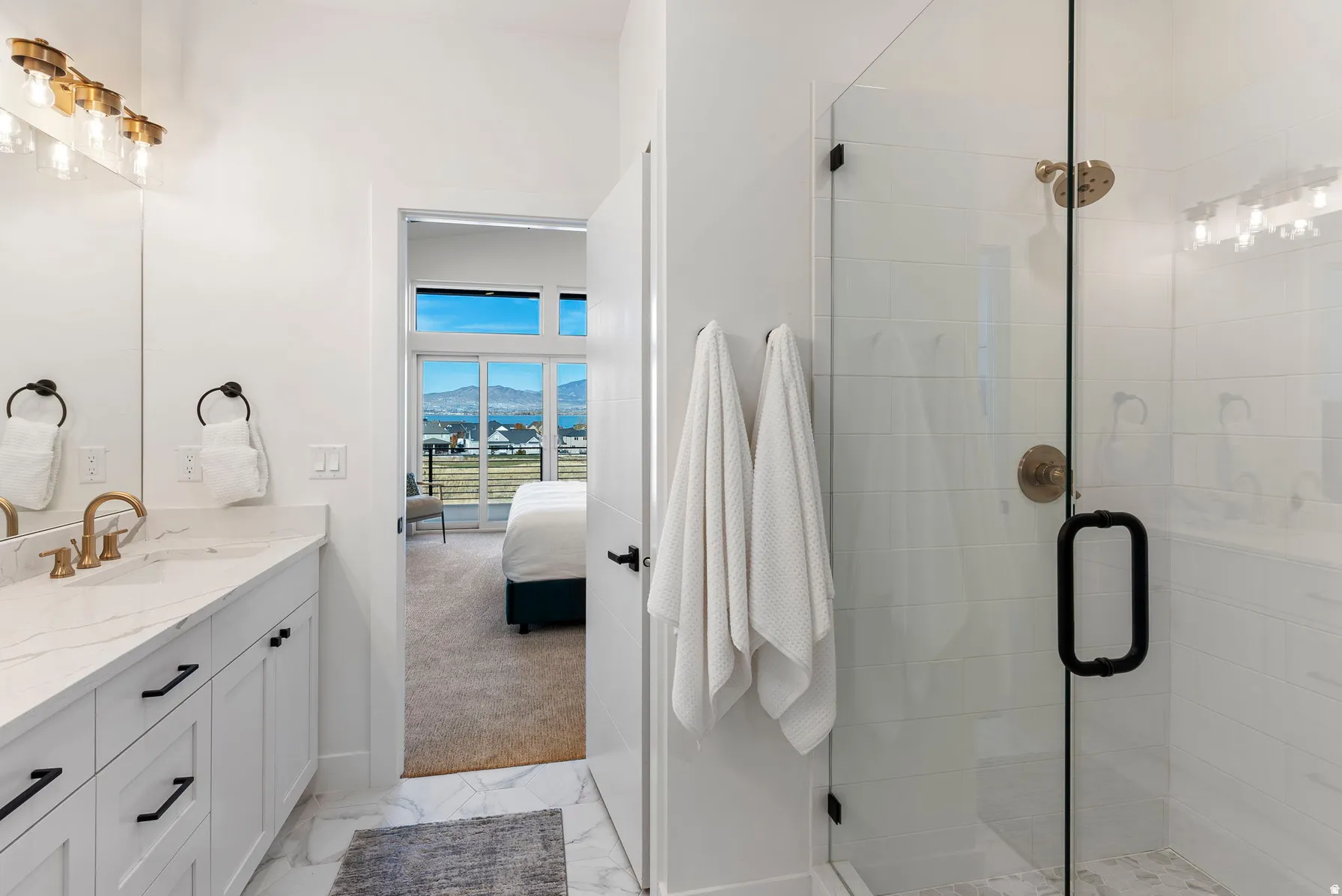 White vanity with a marble-finish countertop, gold-tone faucet, and black hardware