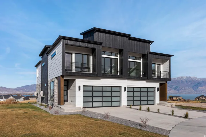 Contemporary exterior with mixed material siding, two prominent balconies, and two modern garage doors with frosted glass panels