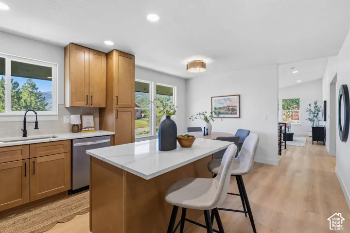 Open-concept kitchen with light wood-finish cabinetry, white countertops, and stainless steel appliances