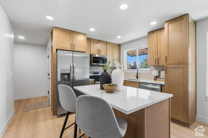 Kitchen featuring light wood-finish cabinetry, stainless steel appliances, a center island with a white countertop, and recessed lighting