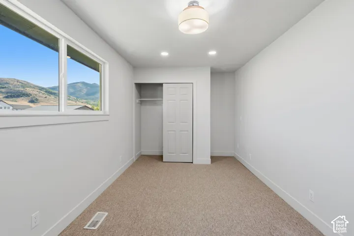 Recessed lighting, carpet flooring, a bifold closet, a semi-flush mount ceiling fixture, and a window with mountain scenery