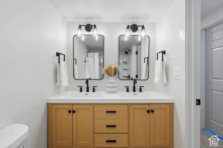 Double vanity with wood-finish cabinetry, integrated sinks, matte black fixtures, and framed mirrors