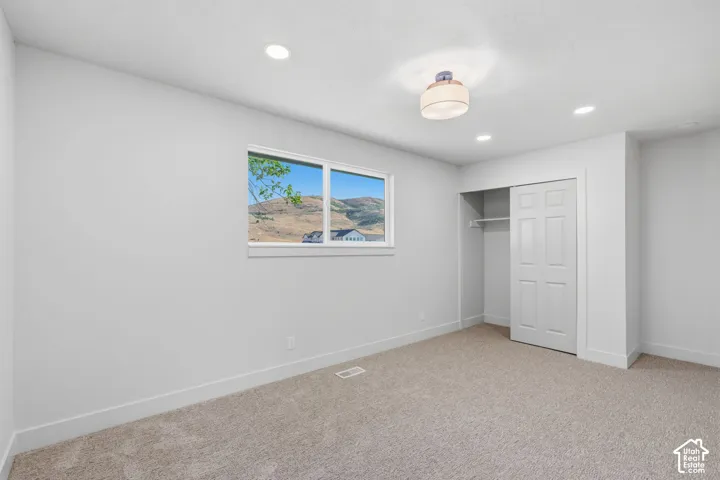 Recessed lighting, flush-mount ceiling fixture, window with exterior scenery, carpet flooring, sliding closet doors