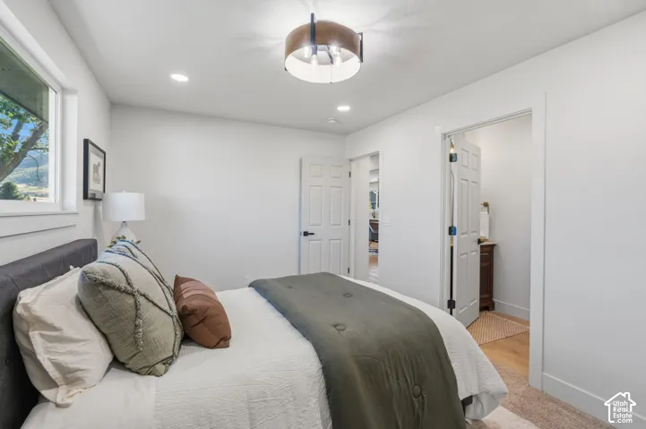 Recessed lighting, contemporary ceiling fixture, white paneled doors, black hardware, wood-finish flooring