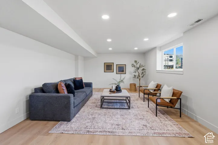 Recessed ceiling lighting, wood-finish flooring, white walls, and a window with white trim