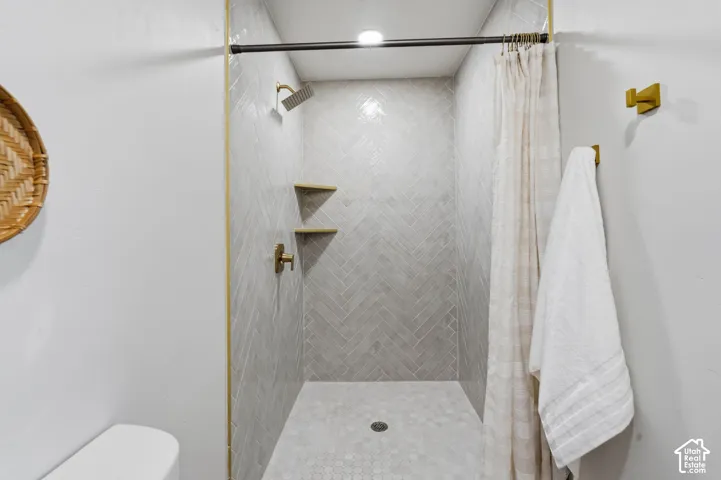 Shower with herringbone tile walls, hexagonal tile flooring, and gold-finish fixtures