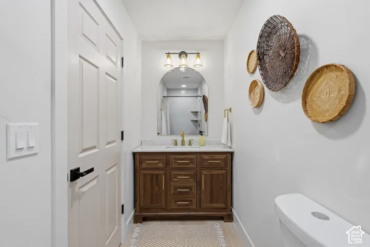 Wood-finish vanity with gold-tone hardware, marble-finish countertop, and arched mirror