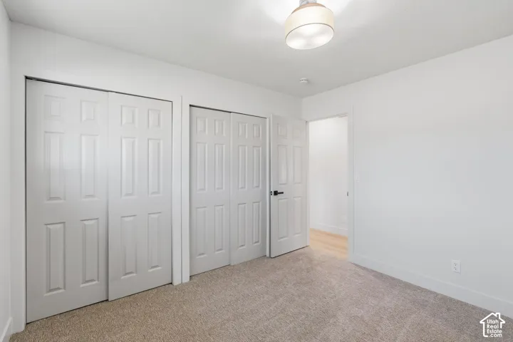 Carpeted flooring, white walls, white trim, paneled closet doors, and an overhead light fixture