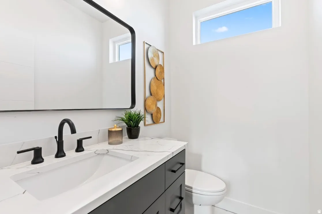 White vanity with a built-in rectangular sink, black hardware, and marble-finish countertop