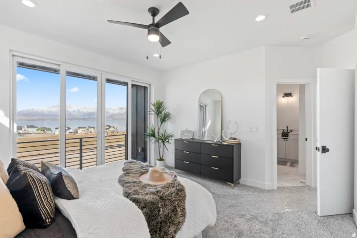 Sliding glass doors opening to a balcony with mountain and water scenery, light gray carpet, recessed lighting, and a contemporary ceiling fan