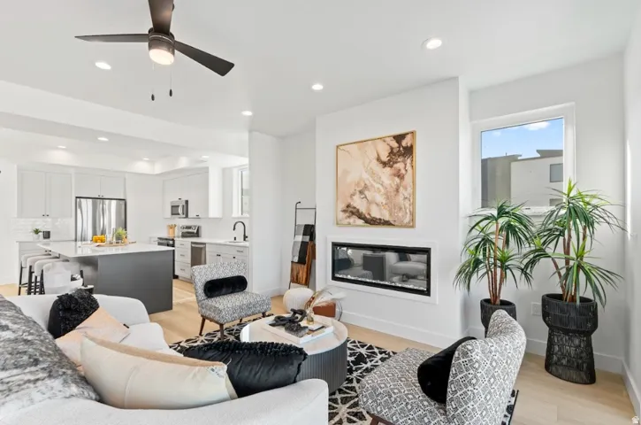 Open-concept living area with wood-finish flooring, recessed lighting, and a modern linear fireplace