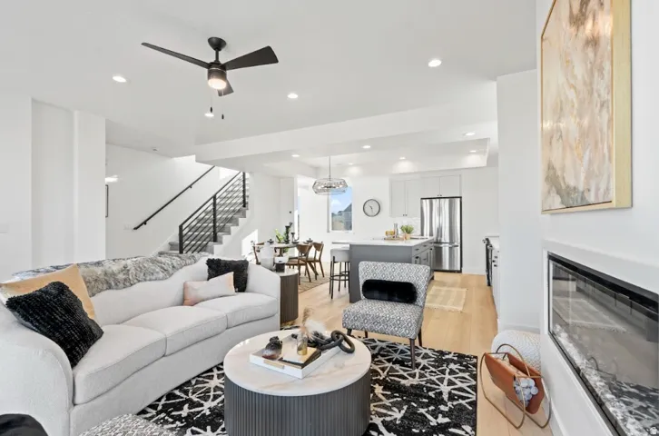 Open-concept living area with wood-finish flooring, a contemporary fireplace, and a modern ceiling fan