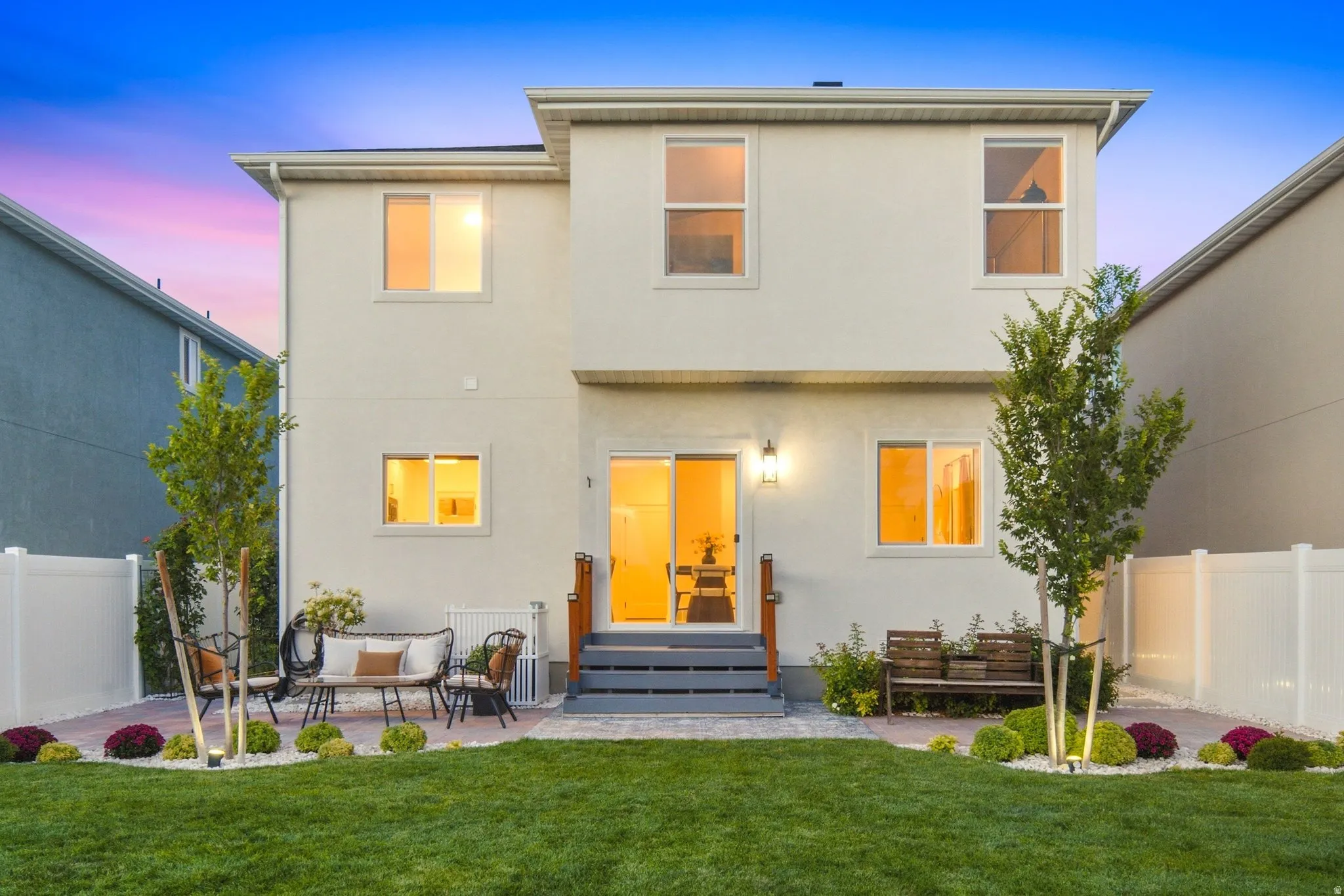 Expansive backyard featuring a manicured lawn, paver patio, and mature landscaping