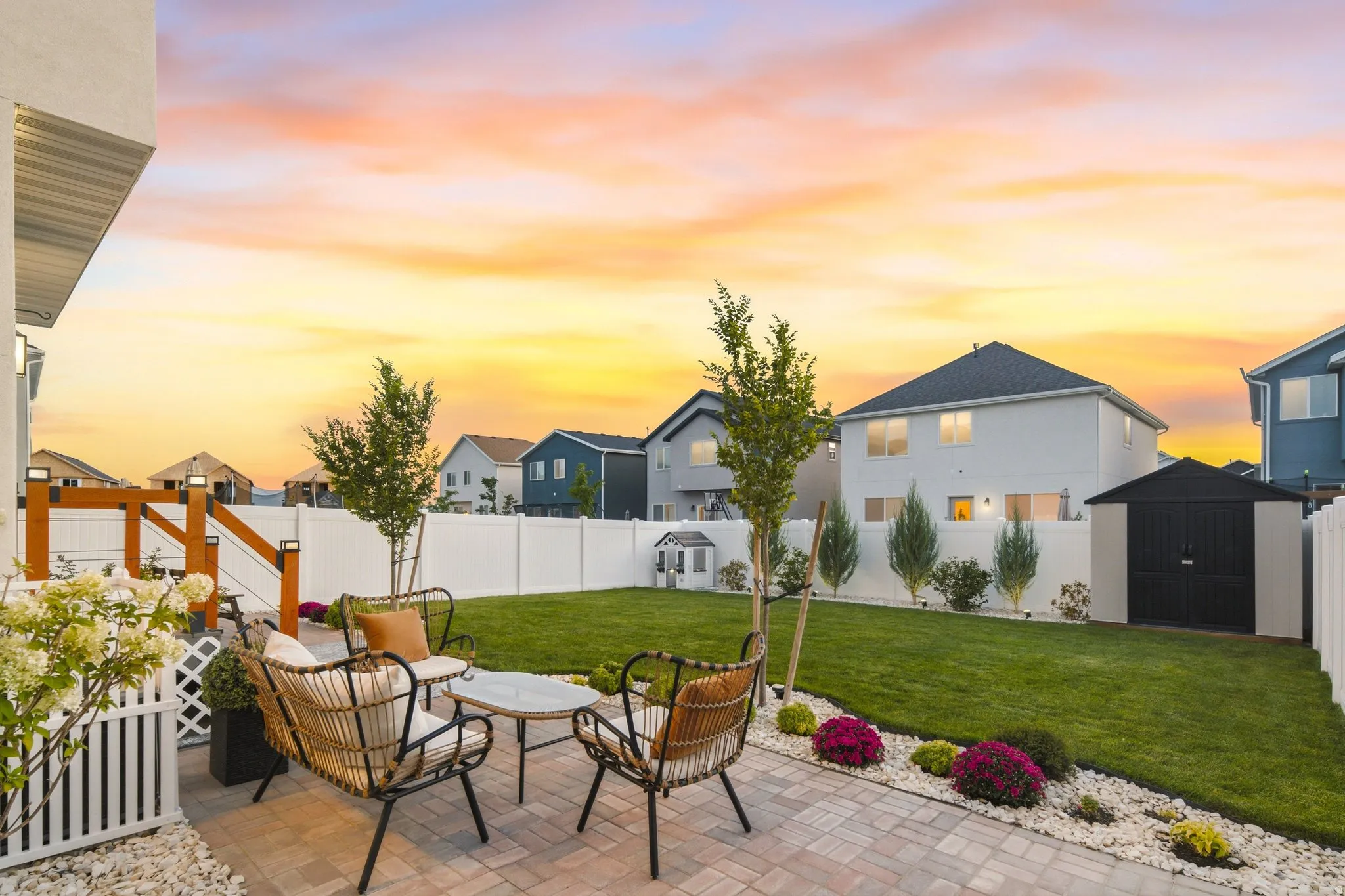 Expansive backyard featuring a paver patio, manicured lawn, storage shed, and full privacy fencing