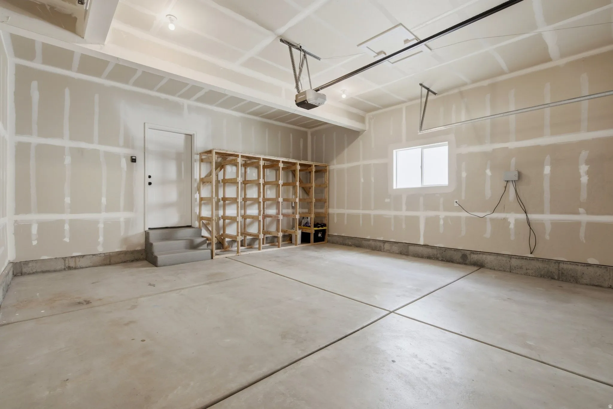 Spacious garage with storage shelves, sprinkler controls and a window.