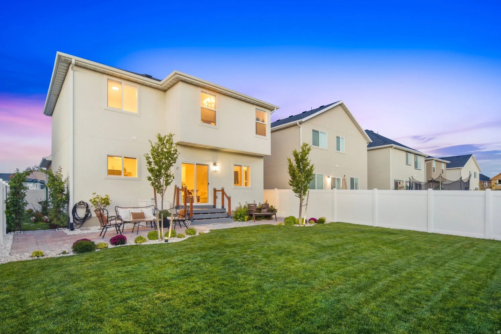 Expansive lawn with a white privacy fence, manicured lawn, and brick paver patio
