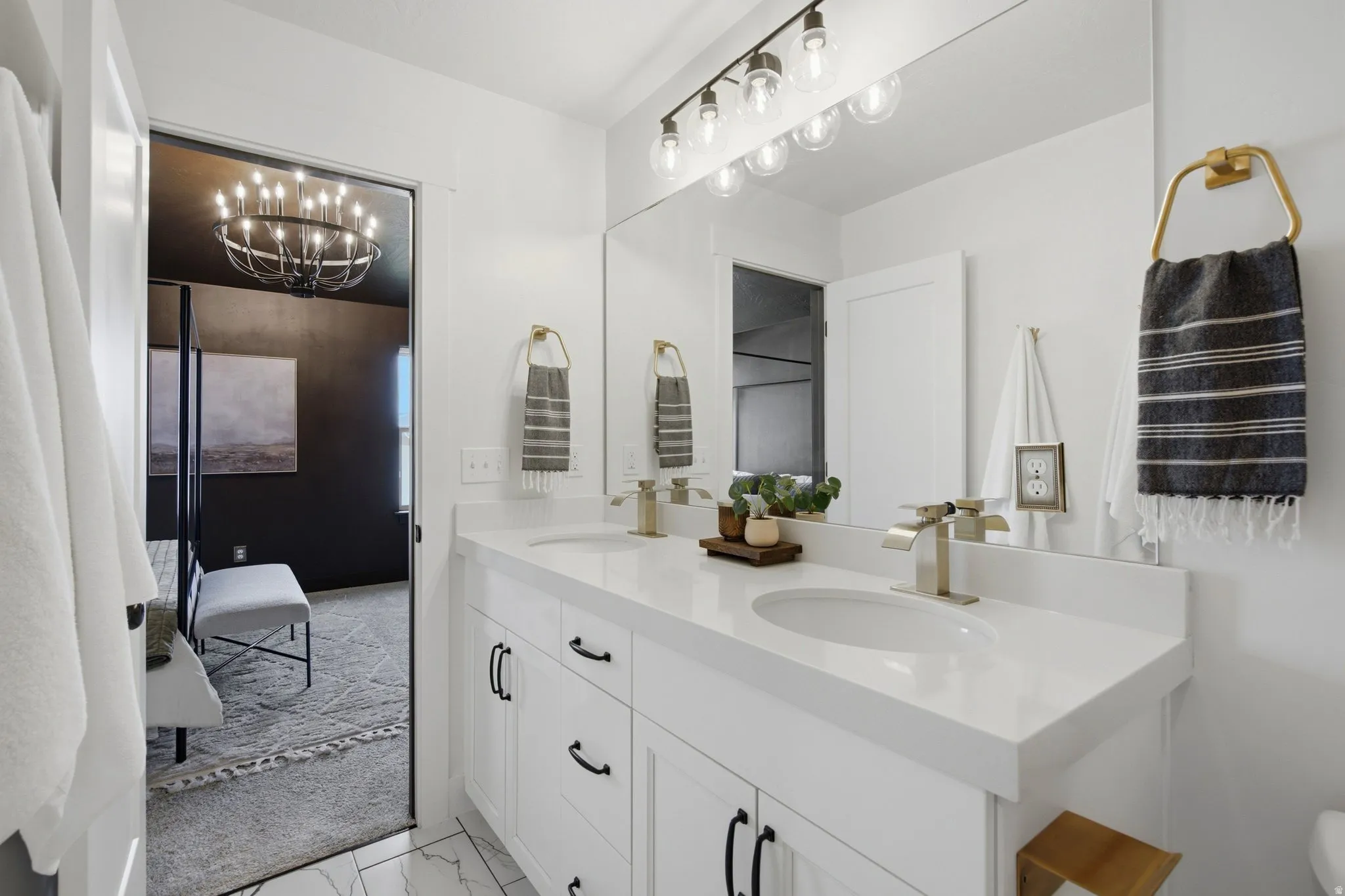 Dual vanity with white cabinetry, matte black hardware, and brushed gold faucets