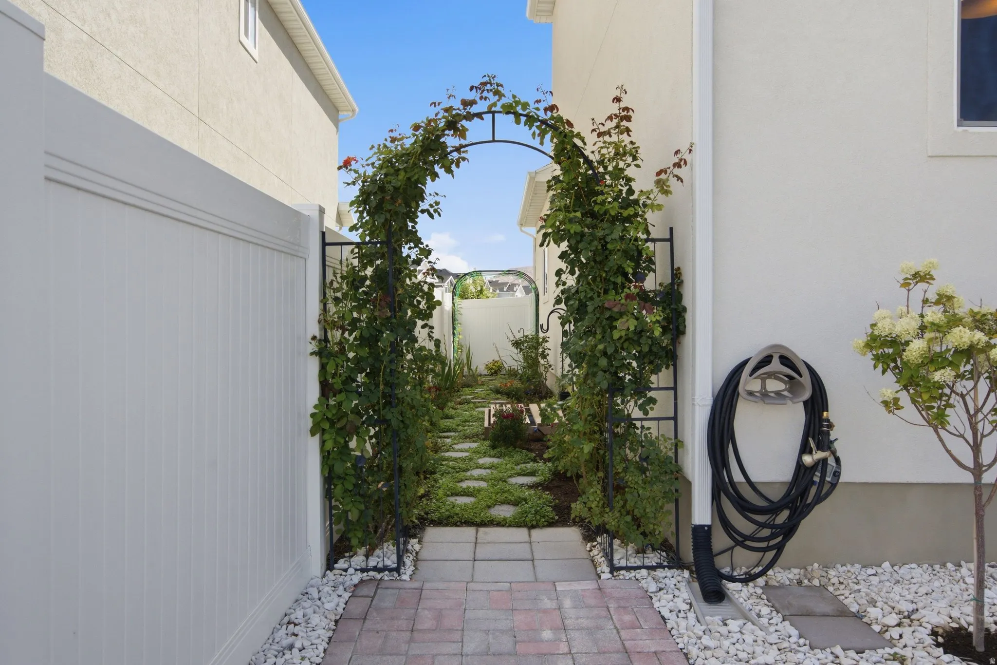Enchanting private side yard/ garden with a climbing plant archway and stepping stone pathway.