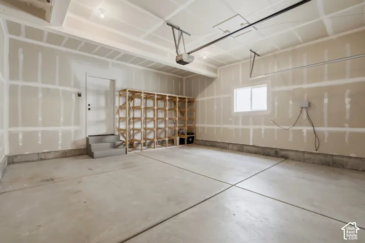Spacious garage with storage shelves, sprinkler controls and a window.