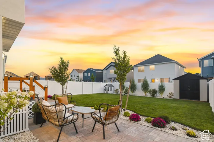 Expansive backyard featuring a paver patio, manicured lawn, storage shed, and full privacy fencing