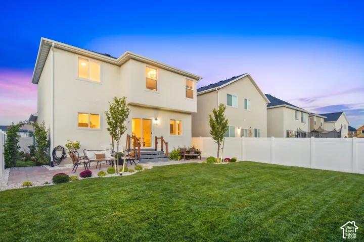 Expansive lawn with a white privacy fence, manicured lawn, and brick paver patio