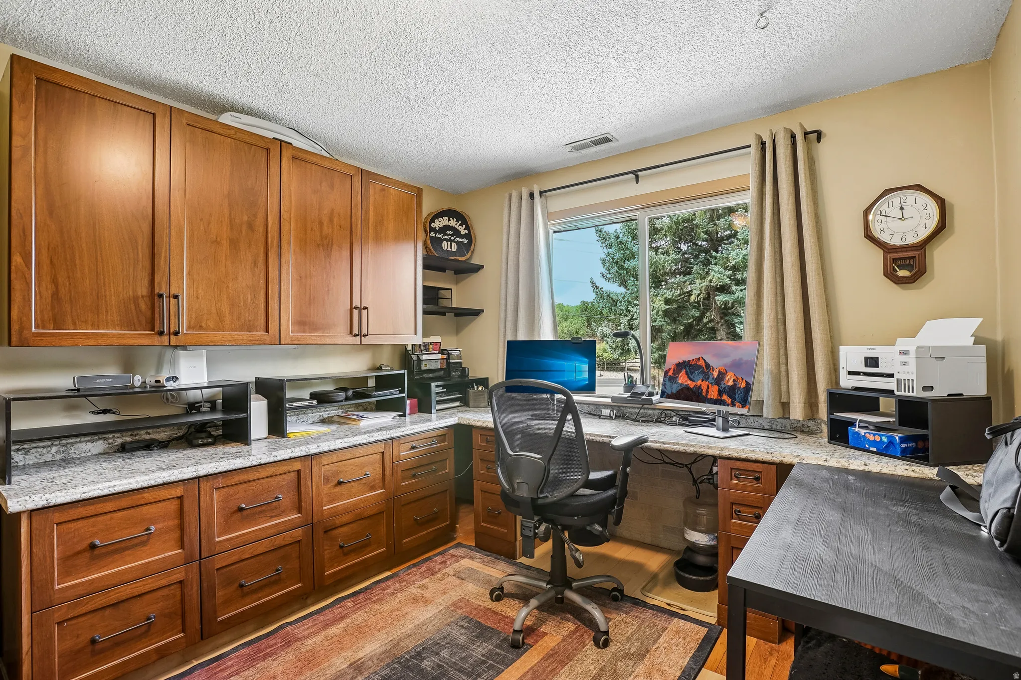 Built-in cabinetry, granite-finish countertops, wood-finish flooring, recessed lighting, and a large window