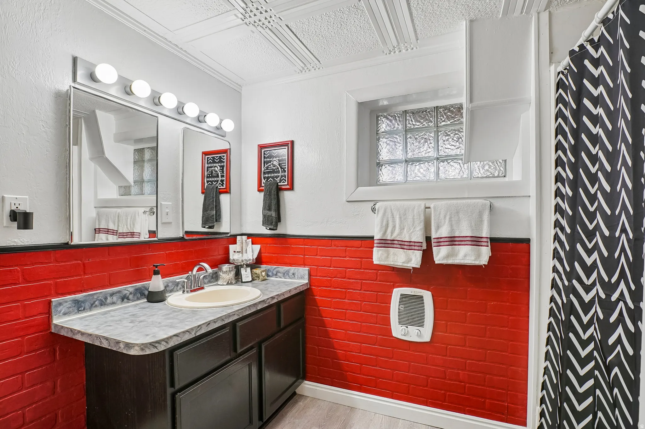 Vanity with an integrated sink, red subway tile wall, textured ceiling, and glass block window