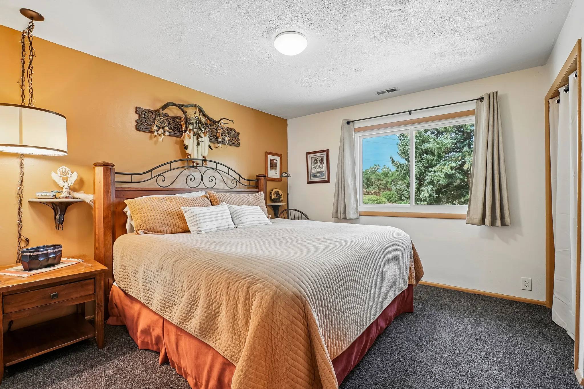 Bedroom featuring carpet flooring, window with natural wood trim, overhead lighting, and a hanging pendant light fixture