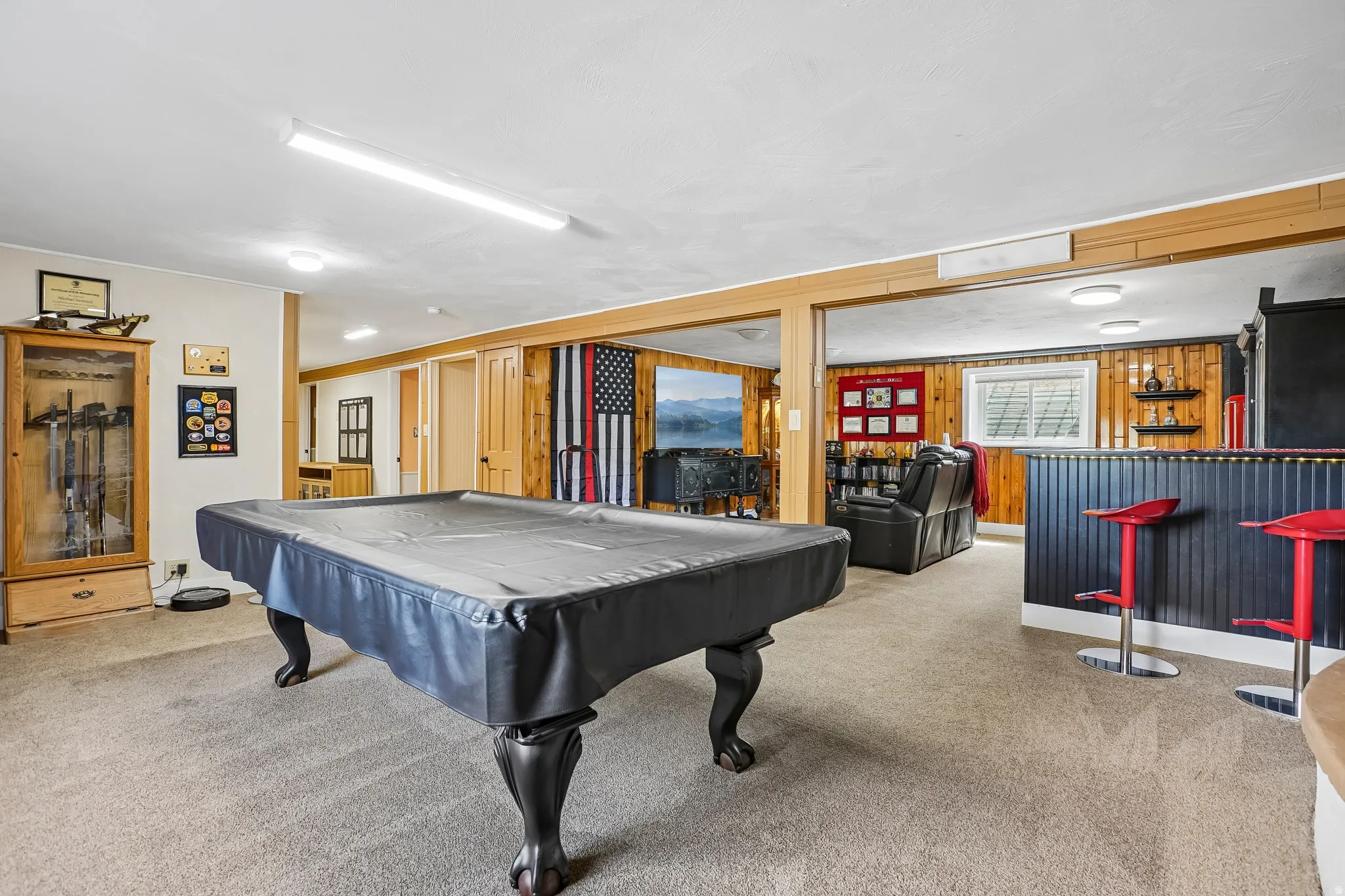 Carpeted recreation room featuring wood-finish paneling, a built-in bar, and recessed lighting
