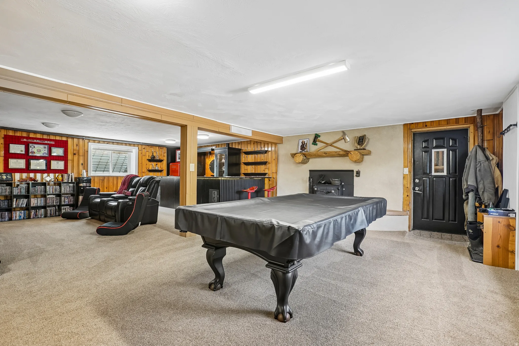 Spacious room with carpet flooring, wood paneling, and a built-in shelf system