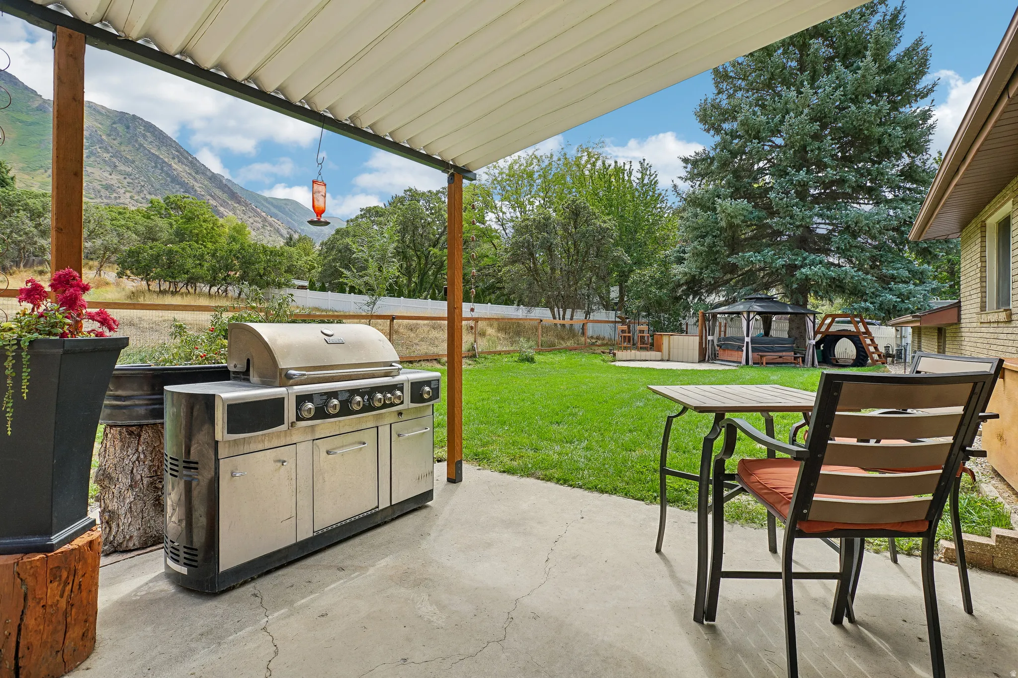 Covered patio with concrete flooring, open-air gazebo, and large grassy area