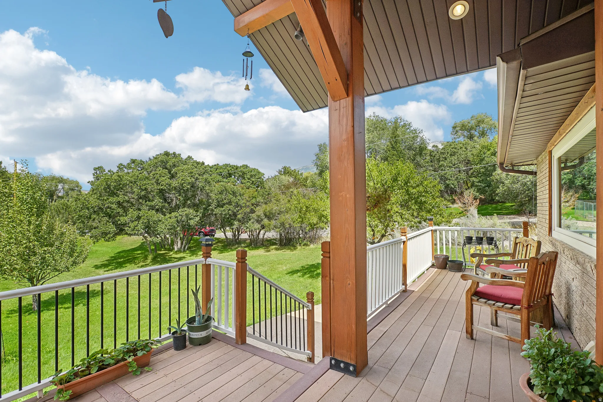 Expansive outdoor deck featuring wood-finish flooring, a black metal railing, and a slatted wood ceiling with recessed lighting