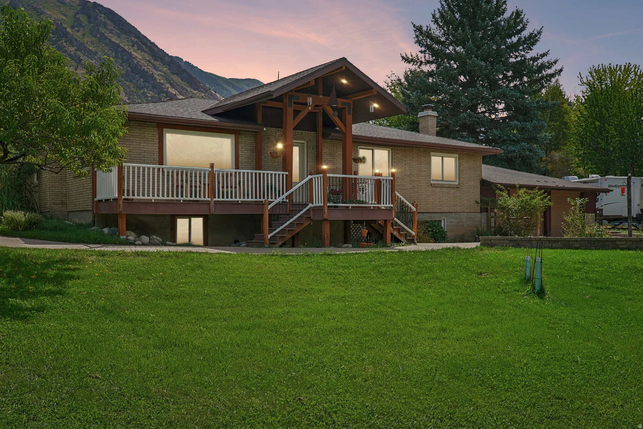Brick exterior with a covered deck, white railing, and exterior lighting