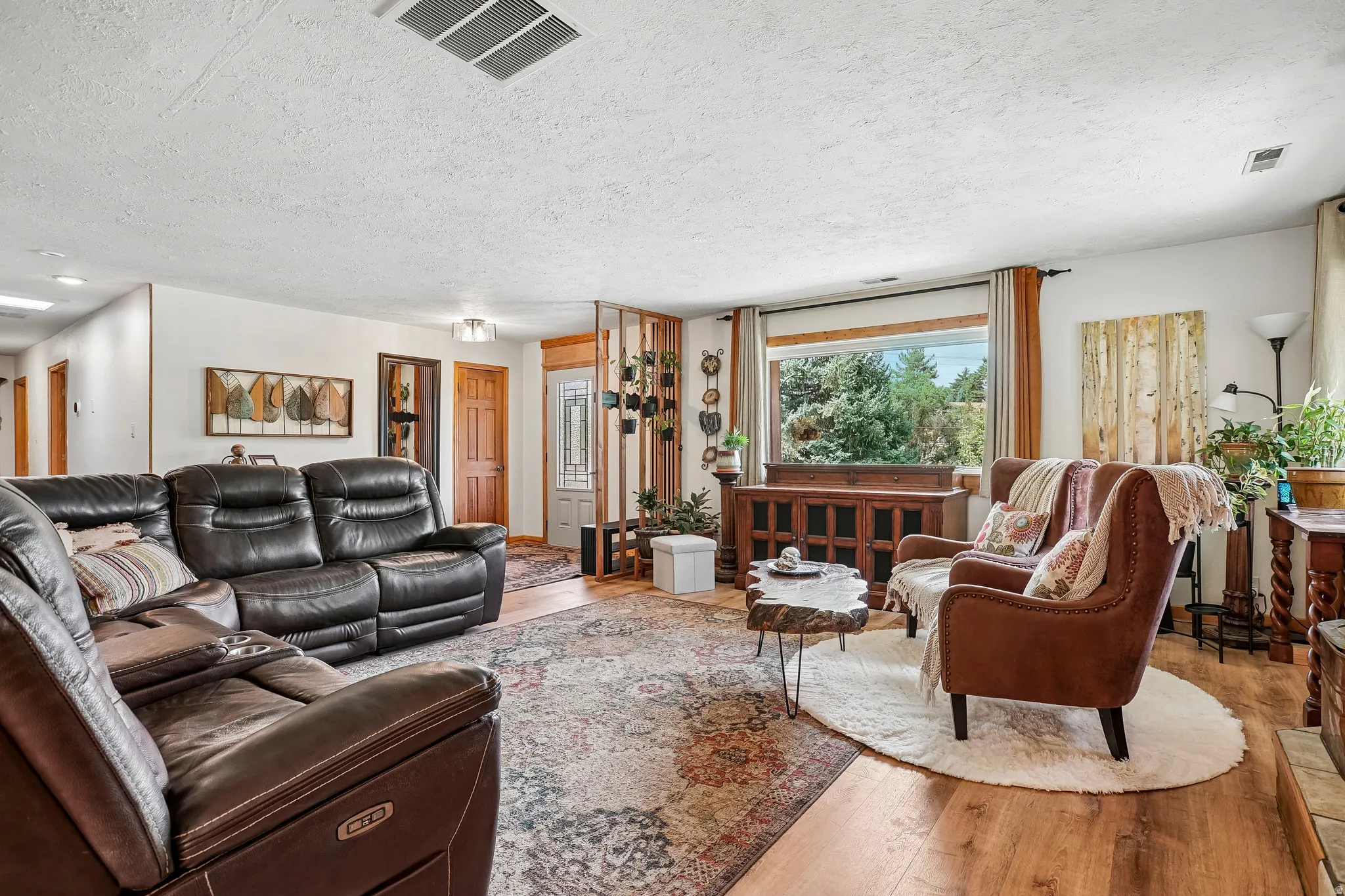Spacious living room featuring recessed ceiling lighting, hardwood flooring, and large windows with natural light
