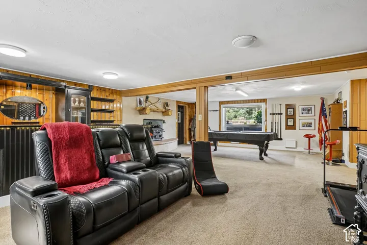 Expansive carpeted recreation room with a built-in bar, wood paneling, and recessed lighting
