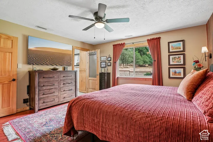 Wood-finish flooring with a ceiling fan, a window with exterior views, and a wall-mounted sconce