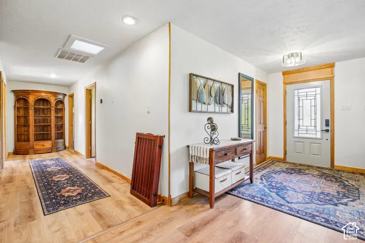 Entryway featuring a white door with decorative glass, wood-finish flooring, and recessed lighting