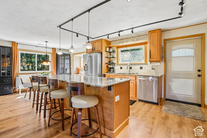 Kitchen with wood-finish flooring, an island featuring a granite countertop, and light wood cabinetry