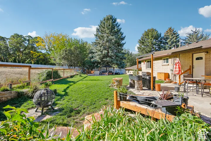 Expansive grassy yard with a privacy fence, concrete patio, and a built-in outdoor cooking area