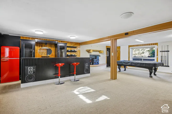 Built-in bar with dark paneling and integrated speakers, wood-paneled feature wall, and recessed ceiling lighting